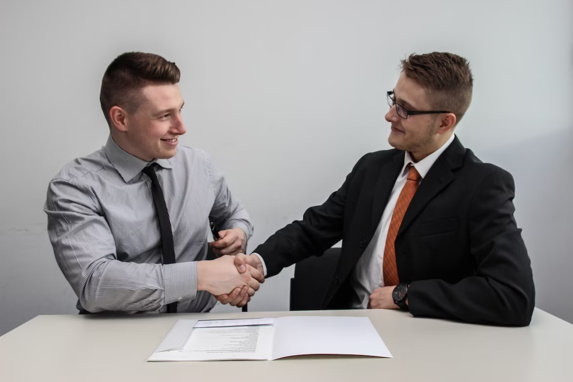 two business men shaking hands over a document